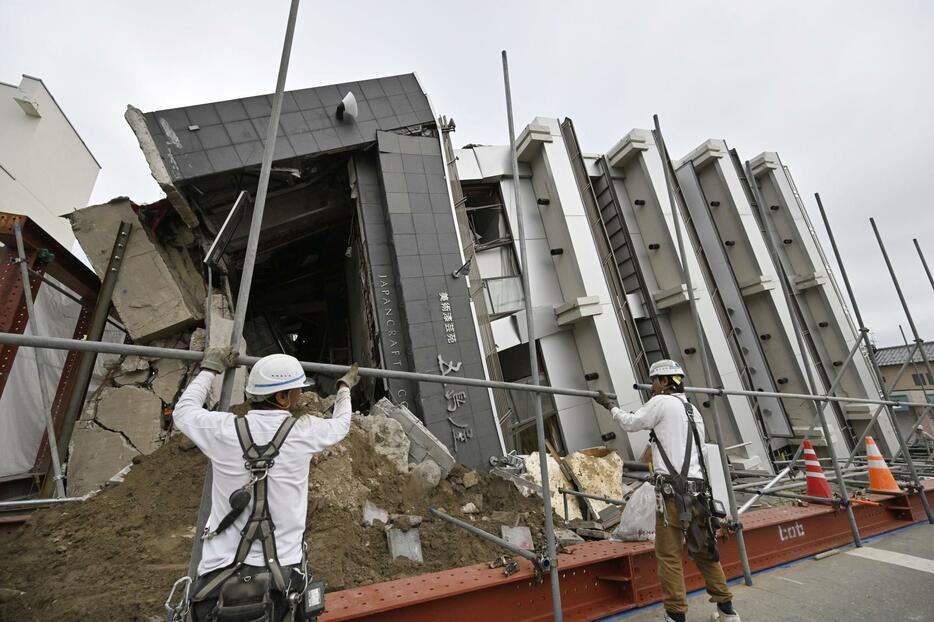 能登半島地震で倒壊し、10カ月となった現在も横倒しのままとなっている石川県輪島市のビル。公費解体に向けた準備が始まった＝1日午後