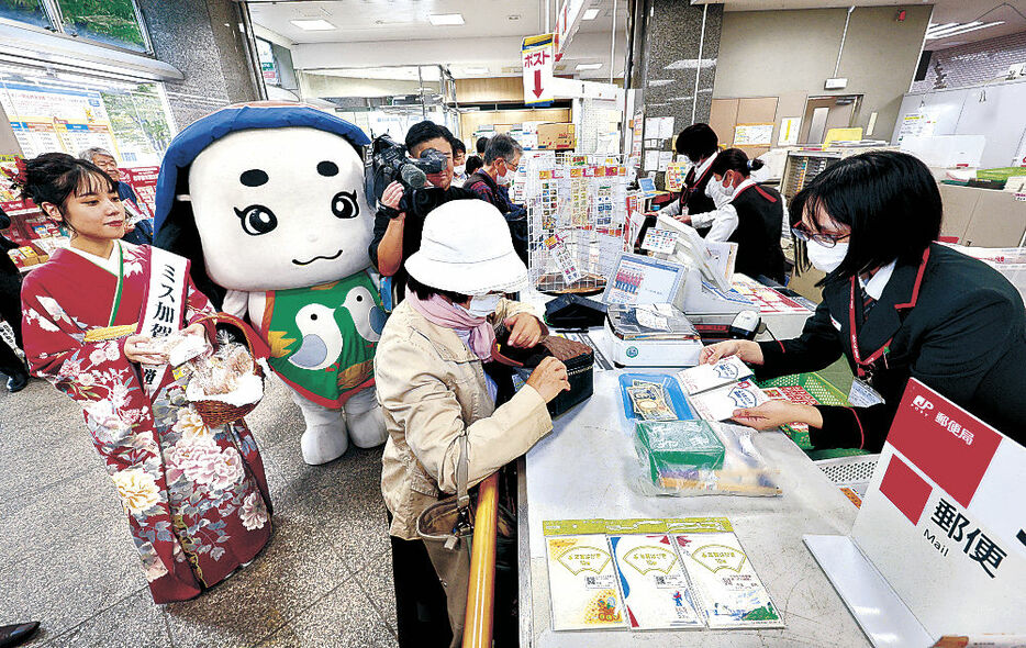 販売が始まった年賀はがきを買い求める人＝１日午前９時２０分、金沢中央郵便局