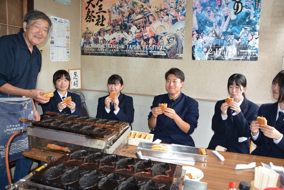 焼きたてのたい焼きを味わう生徒。左は店主の中村忠次郎さん