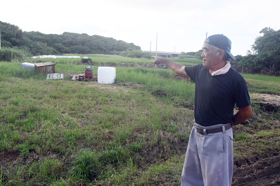 流された牧草ロールを指し示す農家＝14日、鹿児島県与論町麦屋