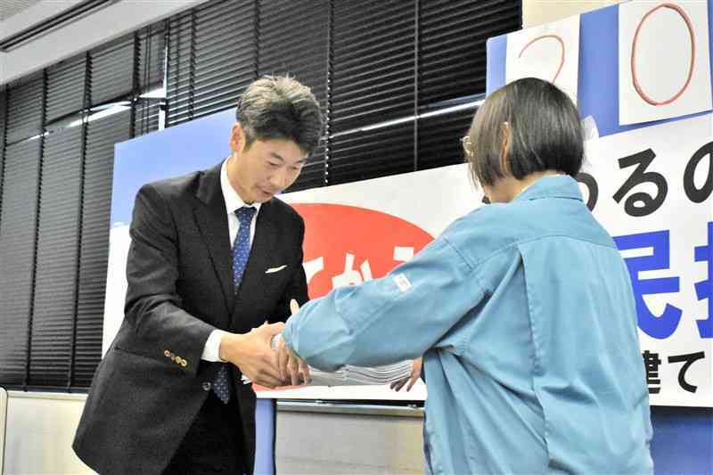 選挙管理委員会の担当者に署名簿を手渡す市民団体の西川文武代表（左）＝26日、熊本市中央区