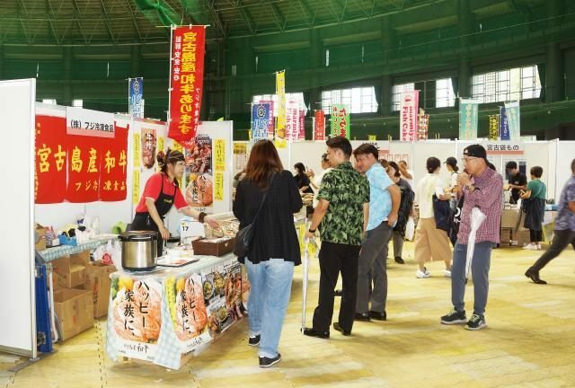 宮古島市や多良間村のブースでは来場者に積極的にアピールしていた＝15日、沖縄セルラーパーク那覇