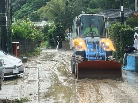 川の氾濫で押し寄せた泥を重機で片付ける地域住民＝10日午前、国頭村比地（竹尾智勇撮影）