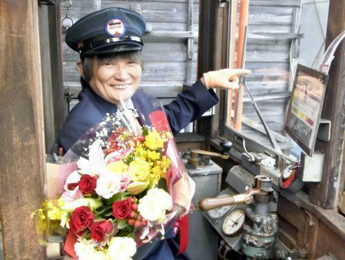 デハニ５０形の体験運転２０００回を祝う花束を手に運転席に座る増田さん（１０月１９日、島根県出雲市で）