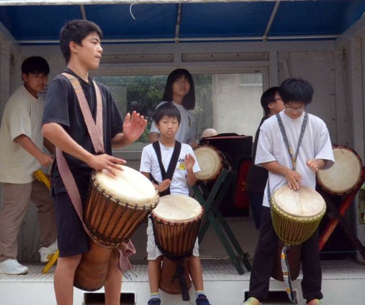 出港する船の乗客に向け、ジャンベの演奏を披露する児童生徒ら＝三島村硫黄島