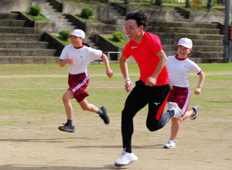 ５０メートル走で児童と競い合う三本木選手（中央）＝京都府南丹市日吉町・殿田小学校