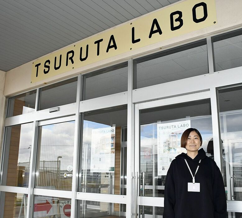 16日にオープンする「TSURUTA　LABO」の玄関前に立つ岡代表