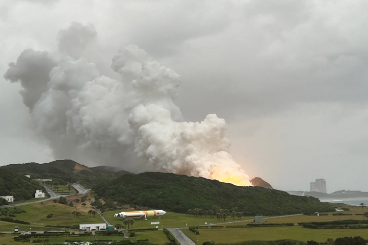 爆発により、試験設備（中央の丘の先）付近から不規則な炎と煙が上がった。なお、試験に使った2段機体のノズル（噴射口）は、向かって右側を向いている＝26日午前、鹿児島県南種子町（JAXA提供）