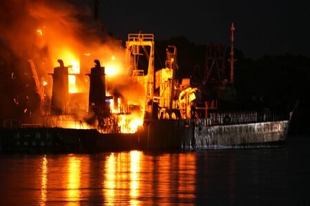 炎を上げて燃える船＝２５日午後６時１２分、今帰仁村の羽地内海