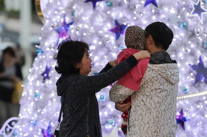 ひんやりとした風が吹く中、幼い子に長袖の上着をかける女性＝27日、午後５時37分、那覇市久茂地（大城直也撮影）