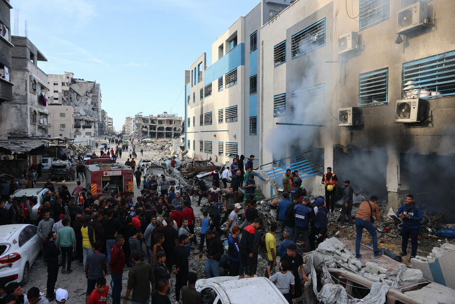 １４日、パレスチナ自治区ガザで、イスラエル軍の空爆を受けた建物の周りに集まる住民ら