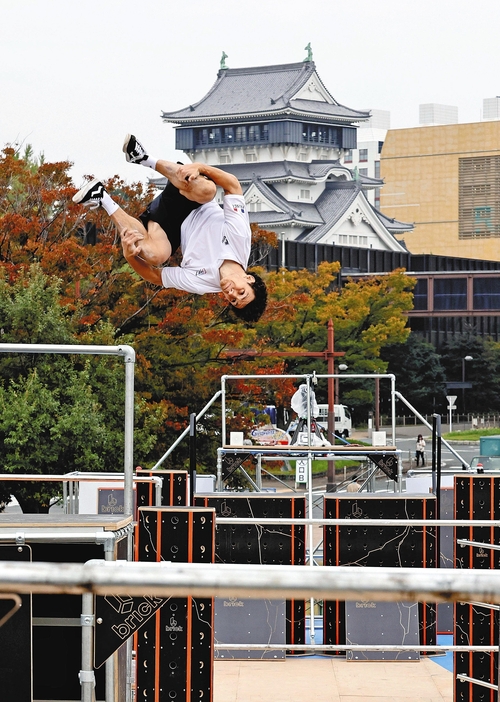 小倉城を背景にアクロバチックな技を披露する選手（16日午前、北九州市小倉北区で）＝長野浩一撮影