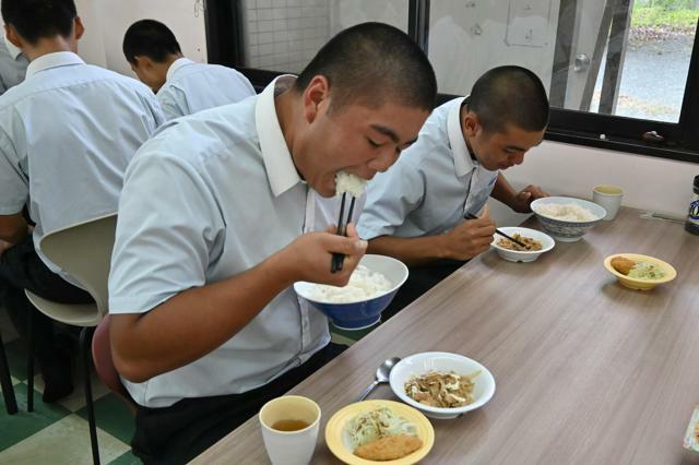 丼に盛ったごはんを食べる硬式野球部の生徒たち=2024年10月8日、福岡県八女市亀甲