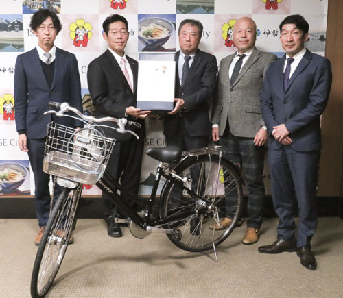 【児童施設に贈る自転車などを鈴木市長（左から2人目）に届けた吉高会長（同3人目）ら＝伊勢市役所で】