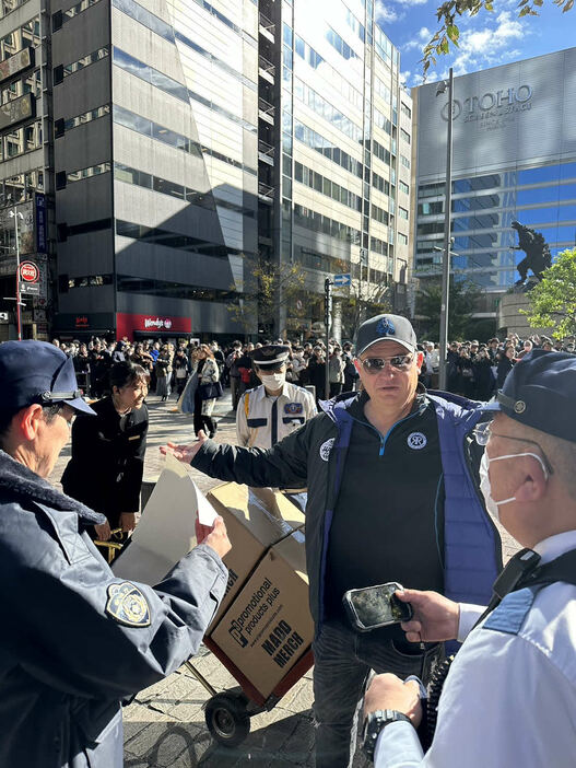 警察官に囲まれるゴリアットのジョン・スチュワート氏