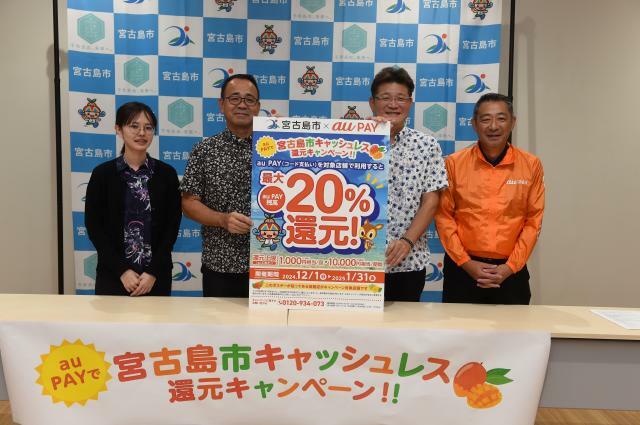 キャンペーンをPRする（写真右から）沖縄セルラーみらいクリエイトの宮平社長、KDDIの宮本営業部長、市観光商工スポーツ部の砂川部長、市観光商工課の職員＝7日、市保健センター