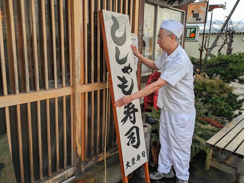 「ししゃも寿司」の看板を店頭に設置する大豊寿司の鈴木佑介さん。休漁が打撃となり、45年の歴史に幕を下ろす