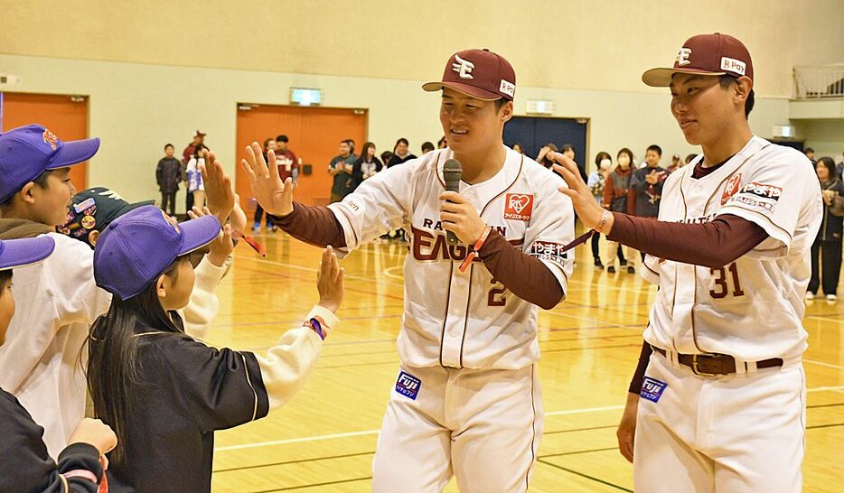 子どもたちとハイタッチを交わす太田選手（左）と渡辺選手＝24日午前、弘前市民体育館