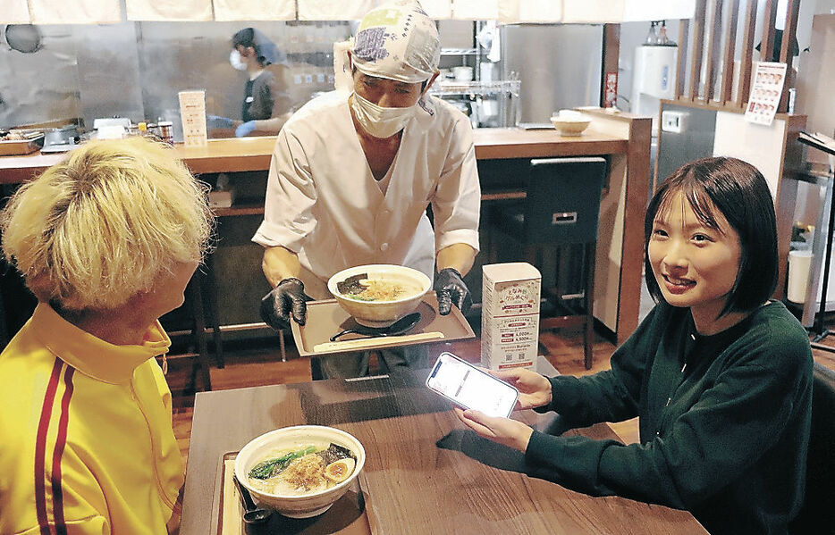 電子チケットを提示し、「白醤油そば」を受け取る来店客＝砺波市太郎丸１丁目