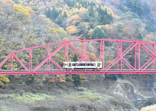 錦秋湖にかかる赤い鉄橋を渡るＪＲ北上線の１両編成の車両（１２日午後、岩手県西和賀町で）