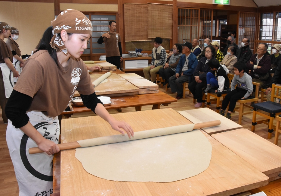 来場者の前でそば打ちを披露する高校生