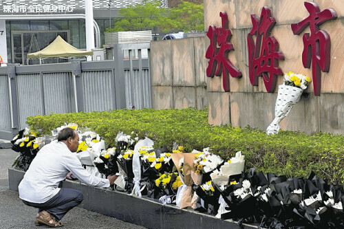 １３日、車の暴走事件が発生した中国広東省珠海市の体育センターで献花する男性＝ＡＰ