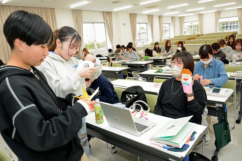 講義で人形を作って見せ合う学生＝青森市の青森中央短期大学