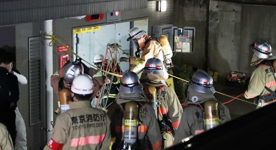 2021年4月15日、地下駐車場の消火設備から二酸化炭素が放出したマンションの入庫口付近で対応に当たる消防関係者ら＝東京都新宿区