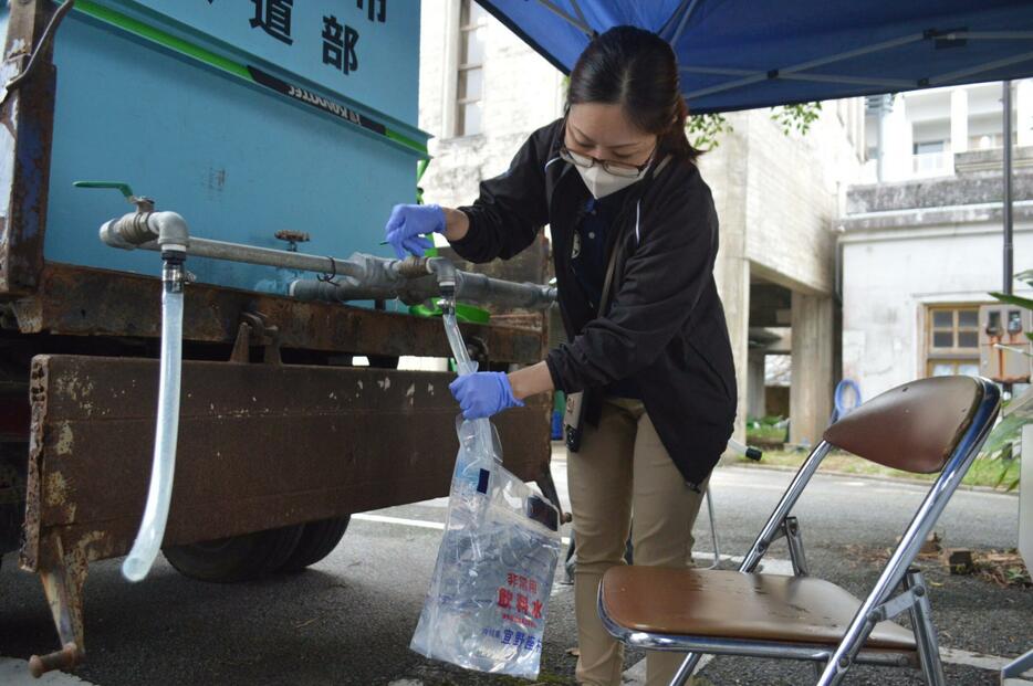 飲料水を袋に入れて準備する大宜味村役場の職員＝13日午後5時ごろ、大宜味村