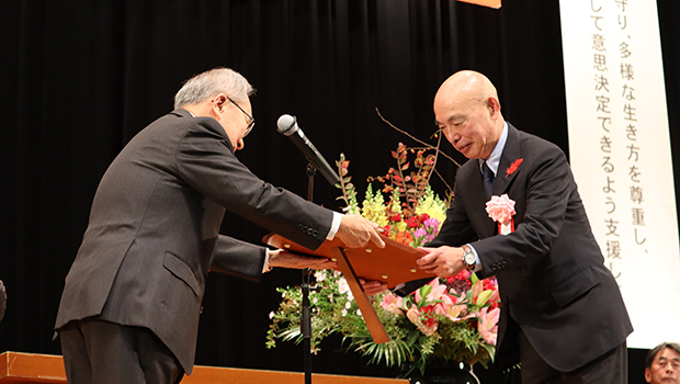 表彰を受ける吉岡理事長（右）