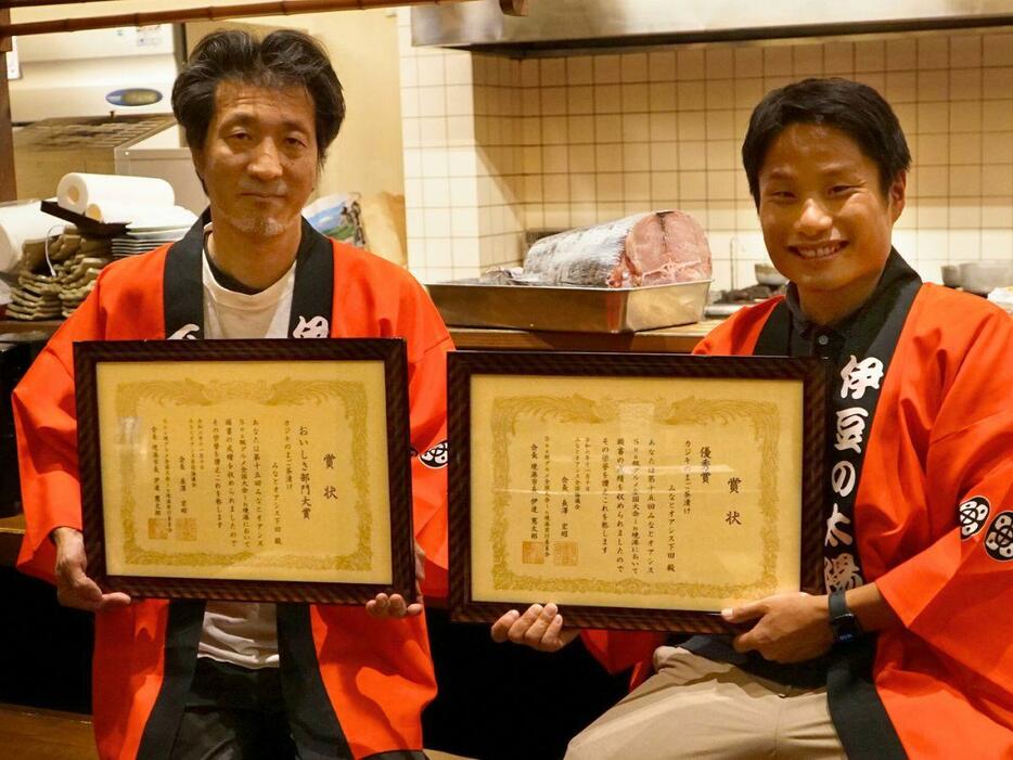 賞状を掲げる「閃味処 料磨」店主の土屋修さん（左）と下田市企画課の佐々木綾さん（右）