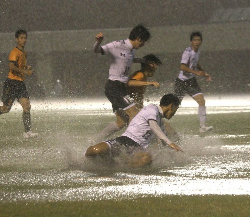 水が浮いたピッチでボールを奪い合う藤枝明誠と浜名の選手たち