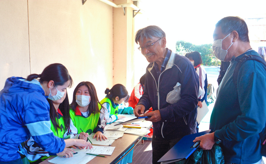 避難者役の地域住民の受付をする生徒たち＝館山