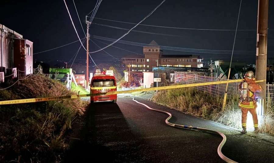 火災現場付近で規制線を張る消防隊員＝１３日午前３時半ごろ、鹿児島市小野町