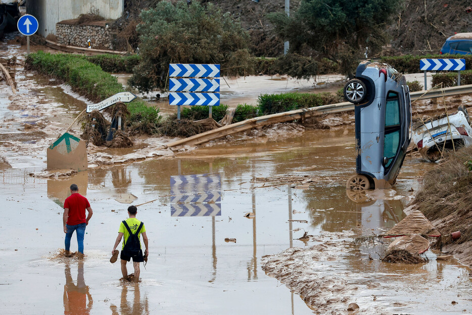 ３１日、洪水の被害を受けたスペイン東部バレンシア自治州で冠水した道路を歩く人々（ＥＰＡ時事）