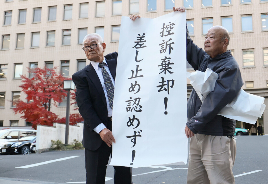 「控訴棄却」などと書かれた紙を掲げる東北電力女川原発差し止め訴訟の原告団＝２７日午後、仙台市青葉区