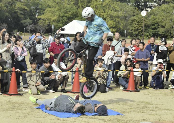 横になった2人を自転車で飛び越える宮岡さん