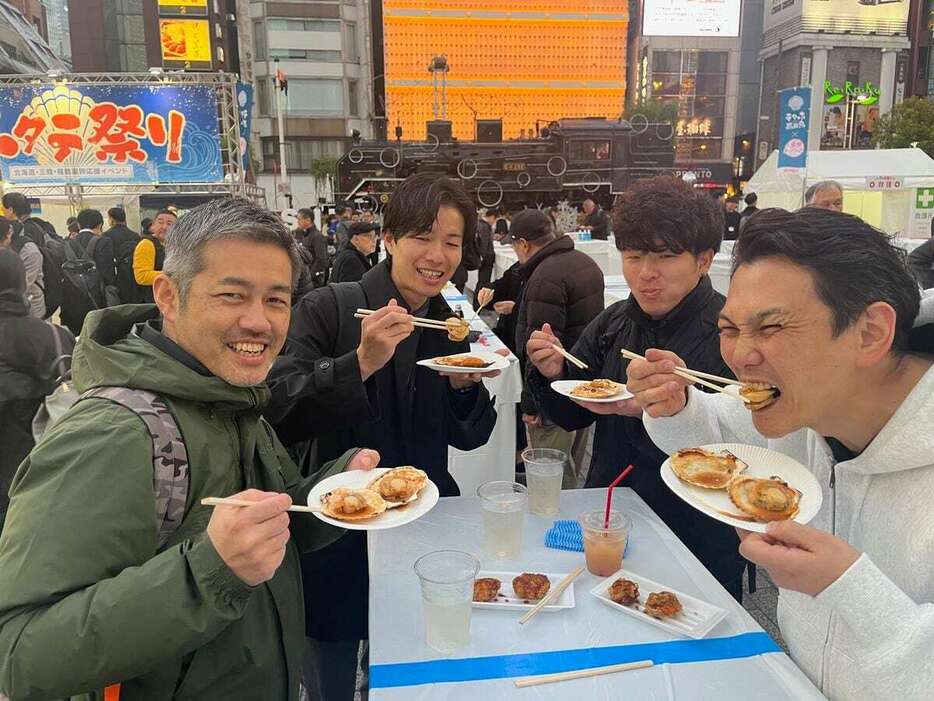 ホタテの浜焼きを味わう仕事帰りの会社員グループ＝21日、東京都港区（小塩史人撮影）