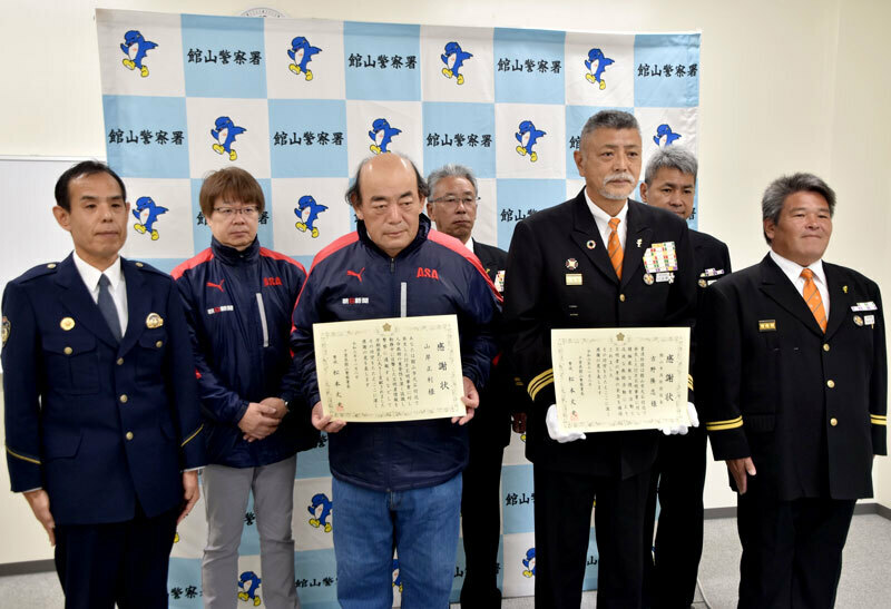 感謝状を掲げる山岸さん（前列左から2人目）と館山市消防団の吉野団長（同3人目）＝8日、館山署