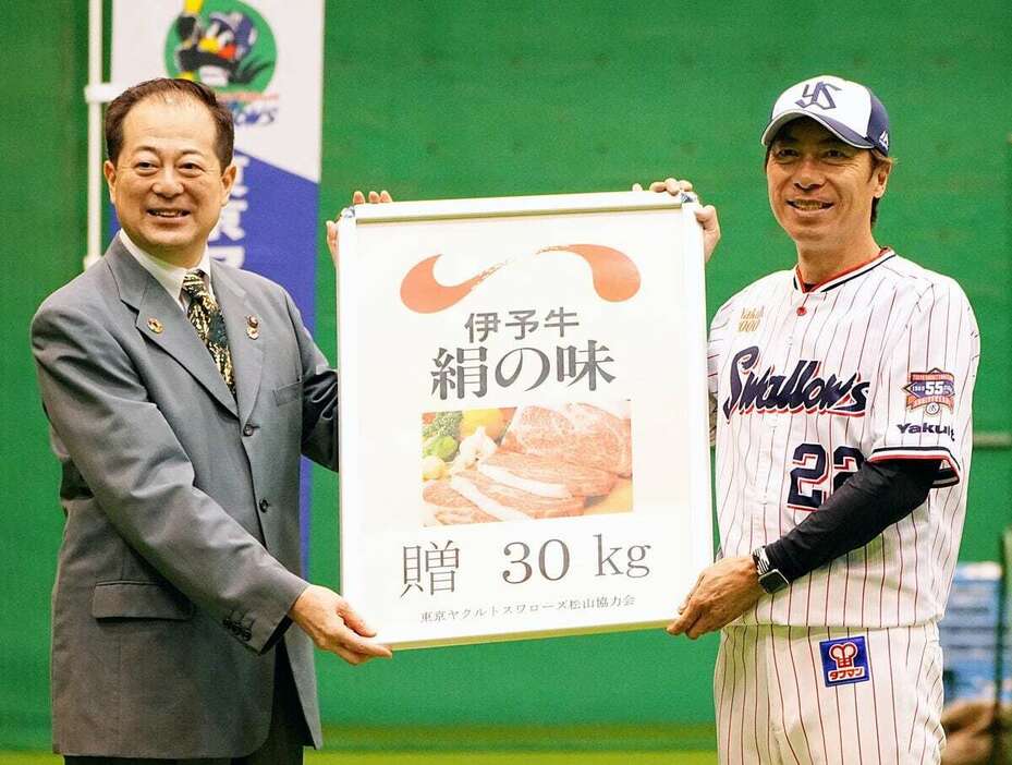 東京ヤクルトスワローズ松山協力会からの差し入れを受け取るヤクルト・高津臣吾監督（右）。左は会長の野志克仁松山市長　＝松山中央公園野球場（坊っちゃんスタジアム）室内練習場（撮影・土谷創造）