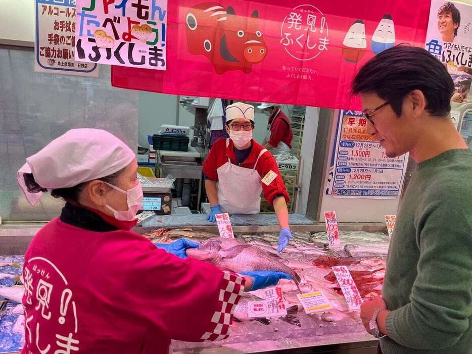 福島を応援したいとクロダイを購入した会社員（右）＝29日、東京都日野市の角上魚類日野店