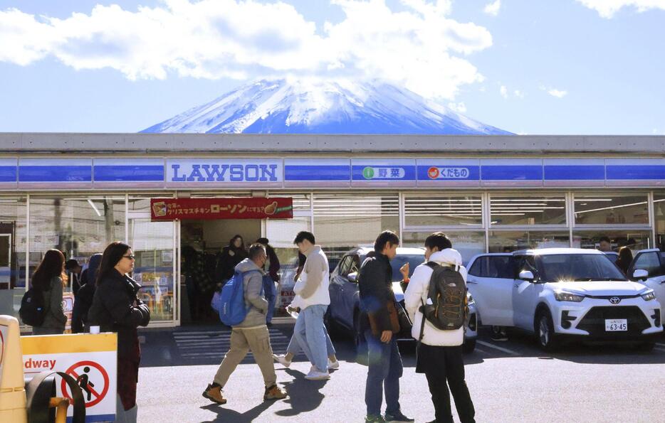 屋根越しに富士山を撮影できるとして訪日観光客らが集まるコンビニ＝29日午後、山梨県富士河口湖町