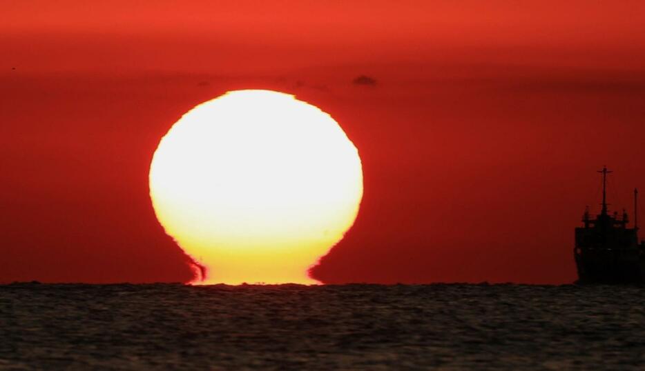 空を赤く染めながら水平線に沈んでいく「だるま夕日」＝１１日夕、神戸市垂水区から播磨灘を望む