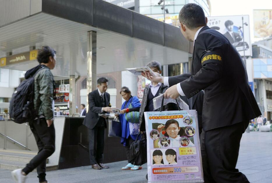 吉川友梨さんの情報提供を求め、大阪・難波でチラシを配る大阪府警の警察官＝20日午後