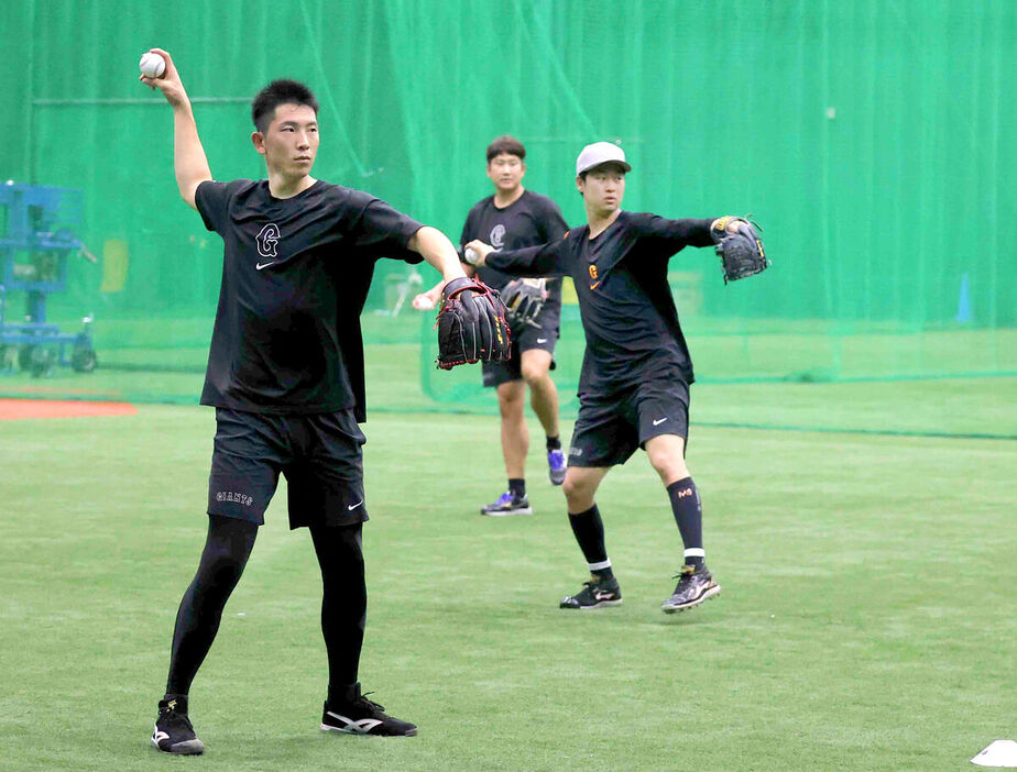 ９月の阪神戦、室内でキャッチボールする戸郷（左）と山崎伊織（奥は菅野）