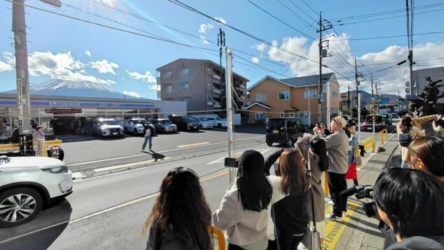 コンビニと富士山の写真を撮影する外国人観光客ら=2024年11月29日午後0時32分、山梨県富士河口湖町、豊平森撮影