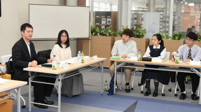 学生や高校生を前に講演する台北駐福岡経済文化弁事処の陳課長（左端）＝９日午前、宮崎市・宮崎産業経営大