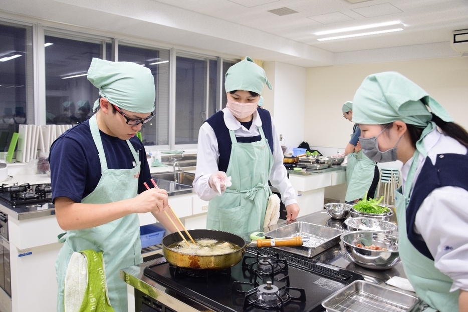 協力しながら鶏肉を揚げる三沢高定時制の生徒