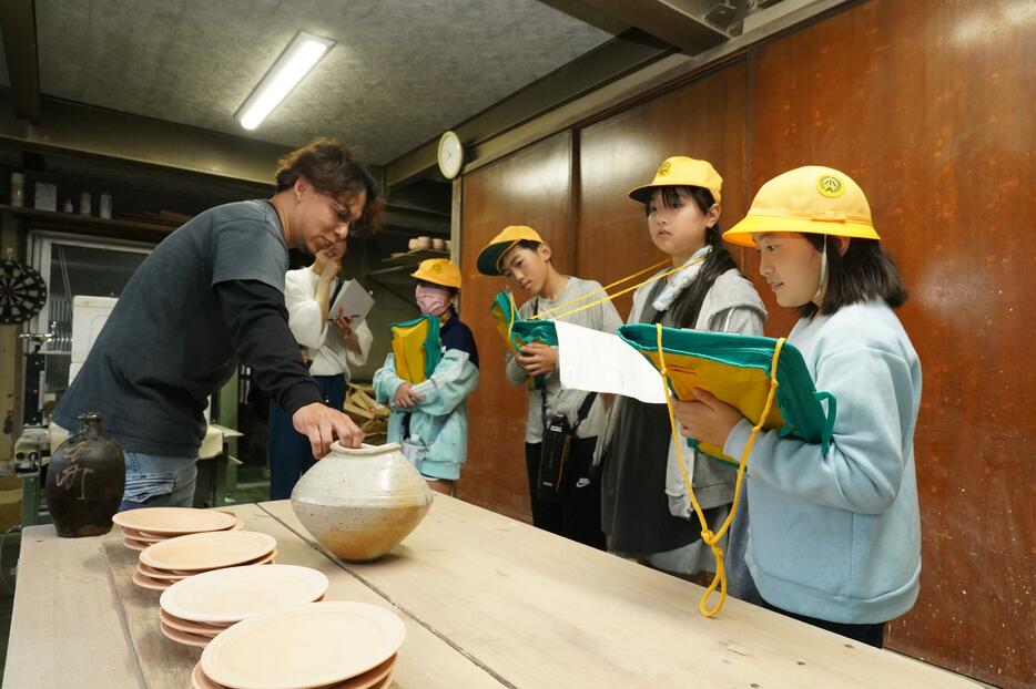 丹波焼陶工の説明に耳を傾けメモを取る児童たち＝兵庫県丹波篠山市今田町上立杭で