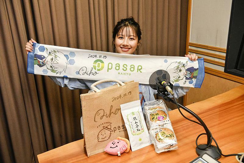 パサール羽生、パサール三芳のグッズや商品とともに笑顔の渡邉さん